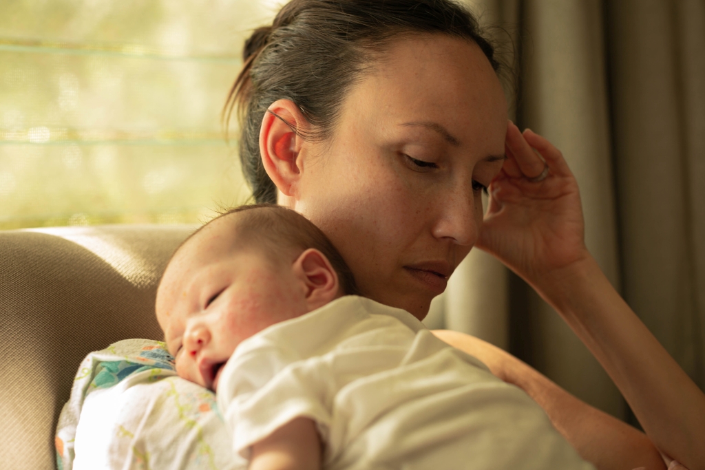 A unhappy mother suffering from postpartum depression, carrying her baby.