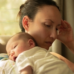 A unhappy mother suffering from postpartum depression, carrying her baby.