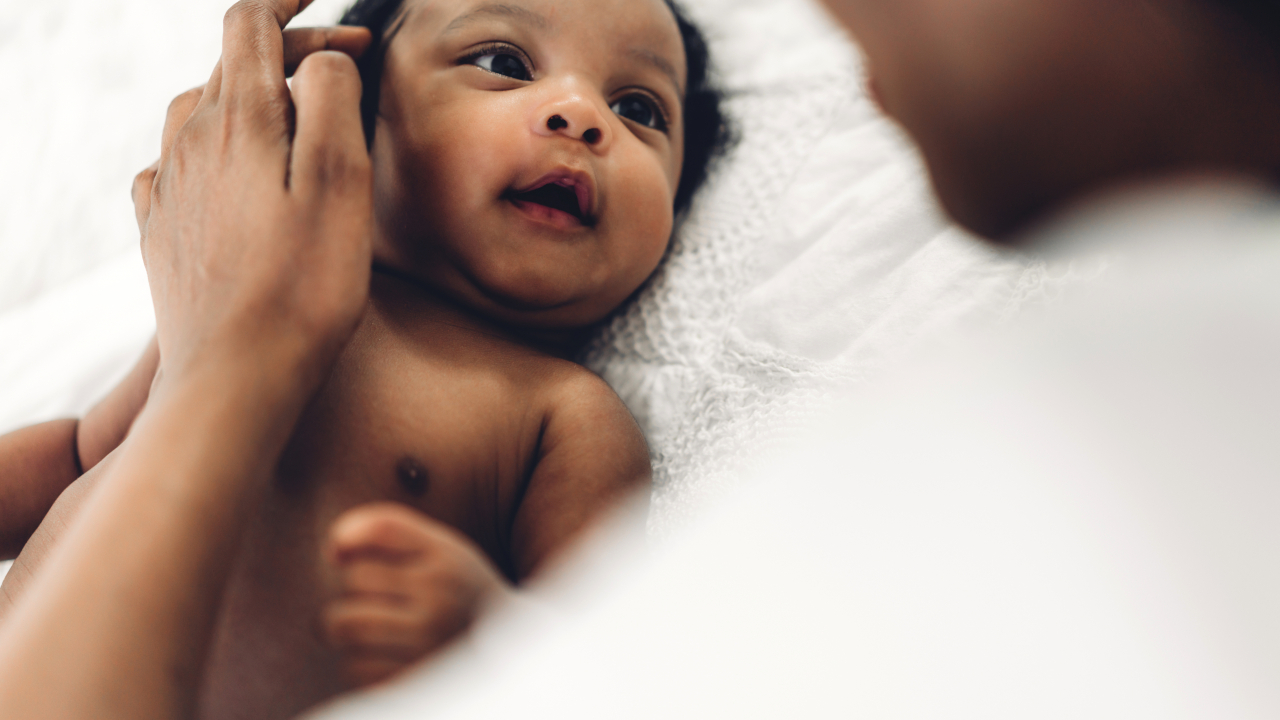 African american mother playing with adorable little african american baby in a white bedroom.Love of black family concept