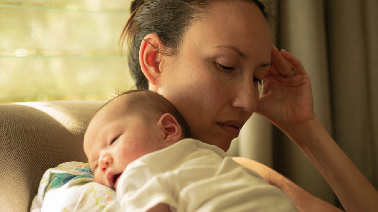 A unhappy mother suffering from postpartum depression, carrying her baby.